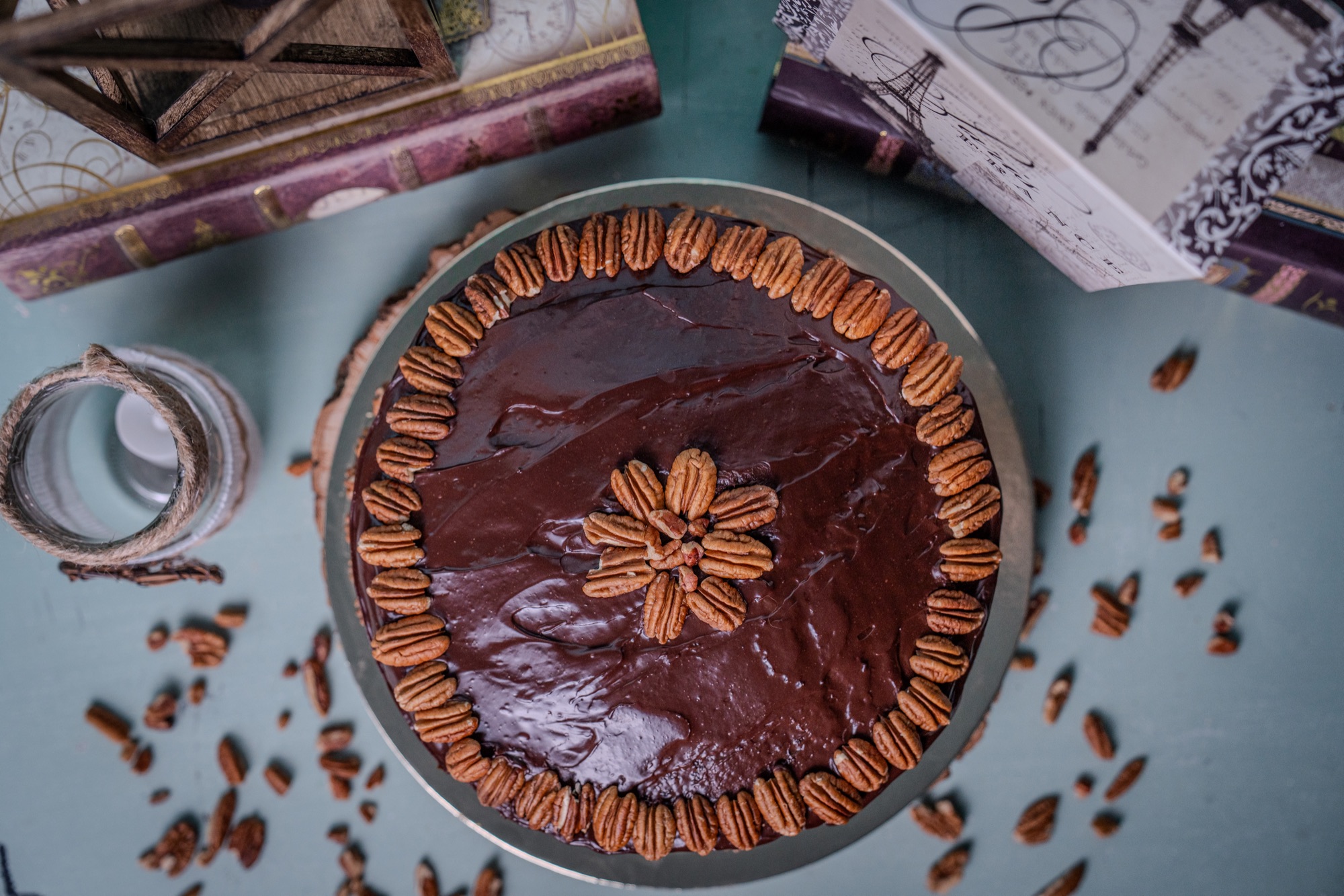 A German chocolate layer cake finished with a ring of pecans, styled with vintage books and candlelight